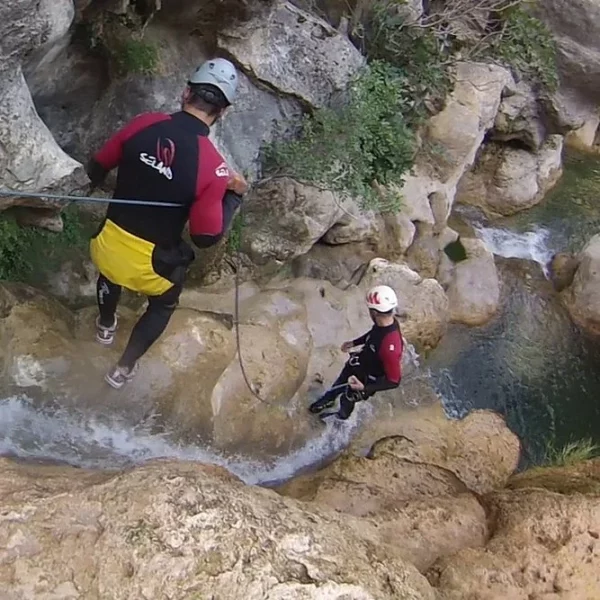 Dos hombres bajando una cascada en una actividad de barranquismo de turismo activo.