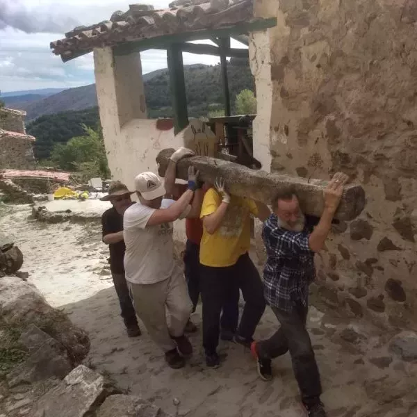 Hombres llevando un tronco al hombre en la Ecoaldea Armejún, ubicada en Soria (Castilla y León).