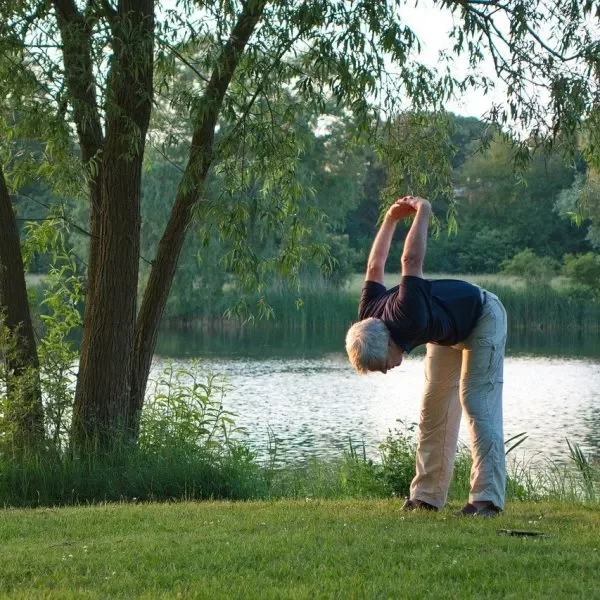 Mujer realizando un ejercicio de yoga a la orilla de un río.