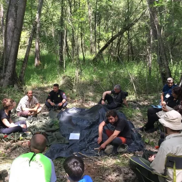 Hombres sentados en circulo en el bosque durante un curso de supervivencia.